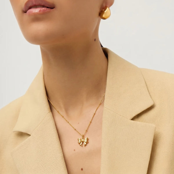 Golden Bow Necklace worn with a beige blazer, close-up on the bow – anti-tarnish pendant necklace for daily wear