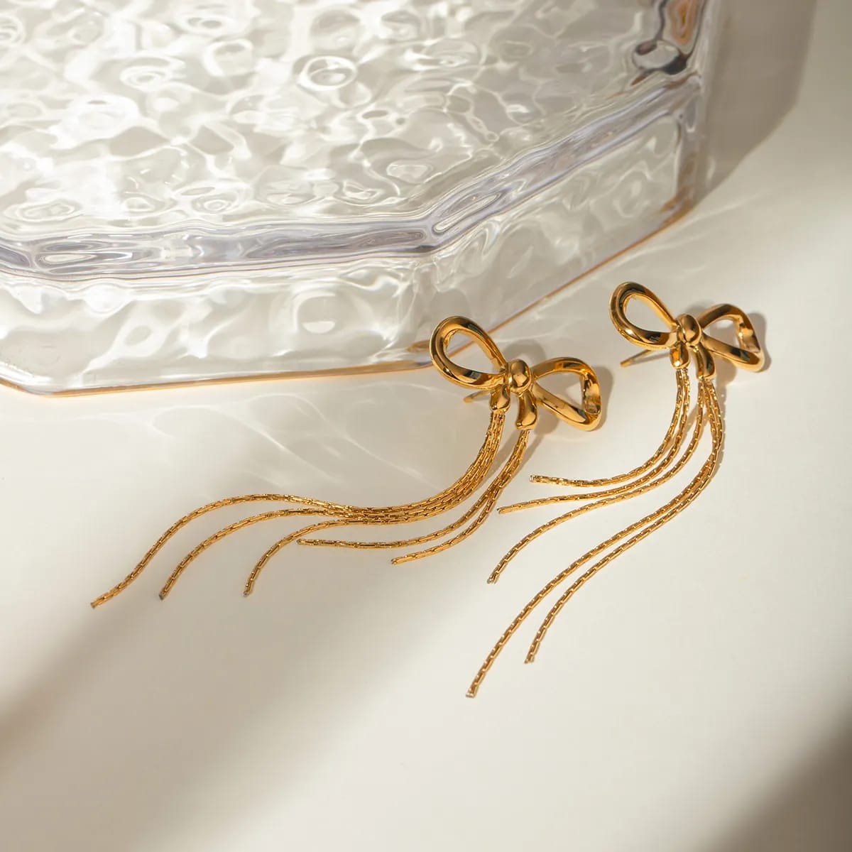 Aurielle Bow Drop Earrings pair styled on a glass surface – anti-tarnish drop earrings for daily wear