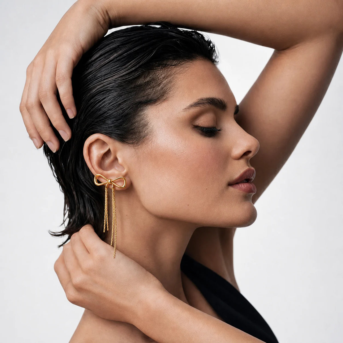 Aurielle Bow Drop Earrings worn by a model with hair swept up, waterproof gold drop earrings