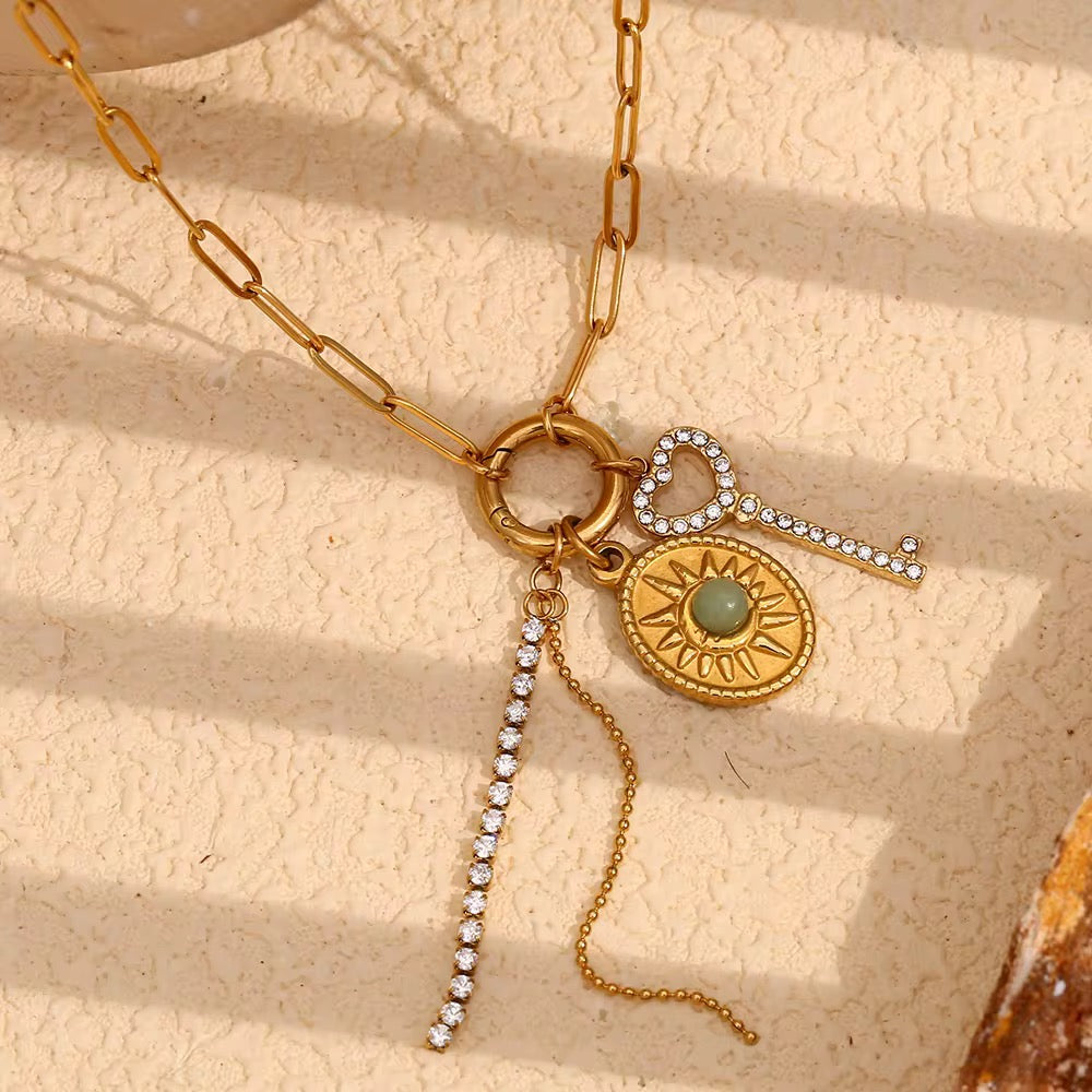 Heart Key Charm Necklace laid out on white showing the heart key, sun medallion and stone charms, waterproof gold charm necklace