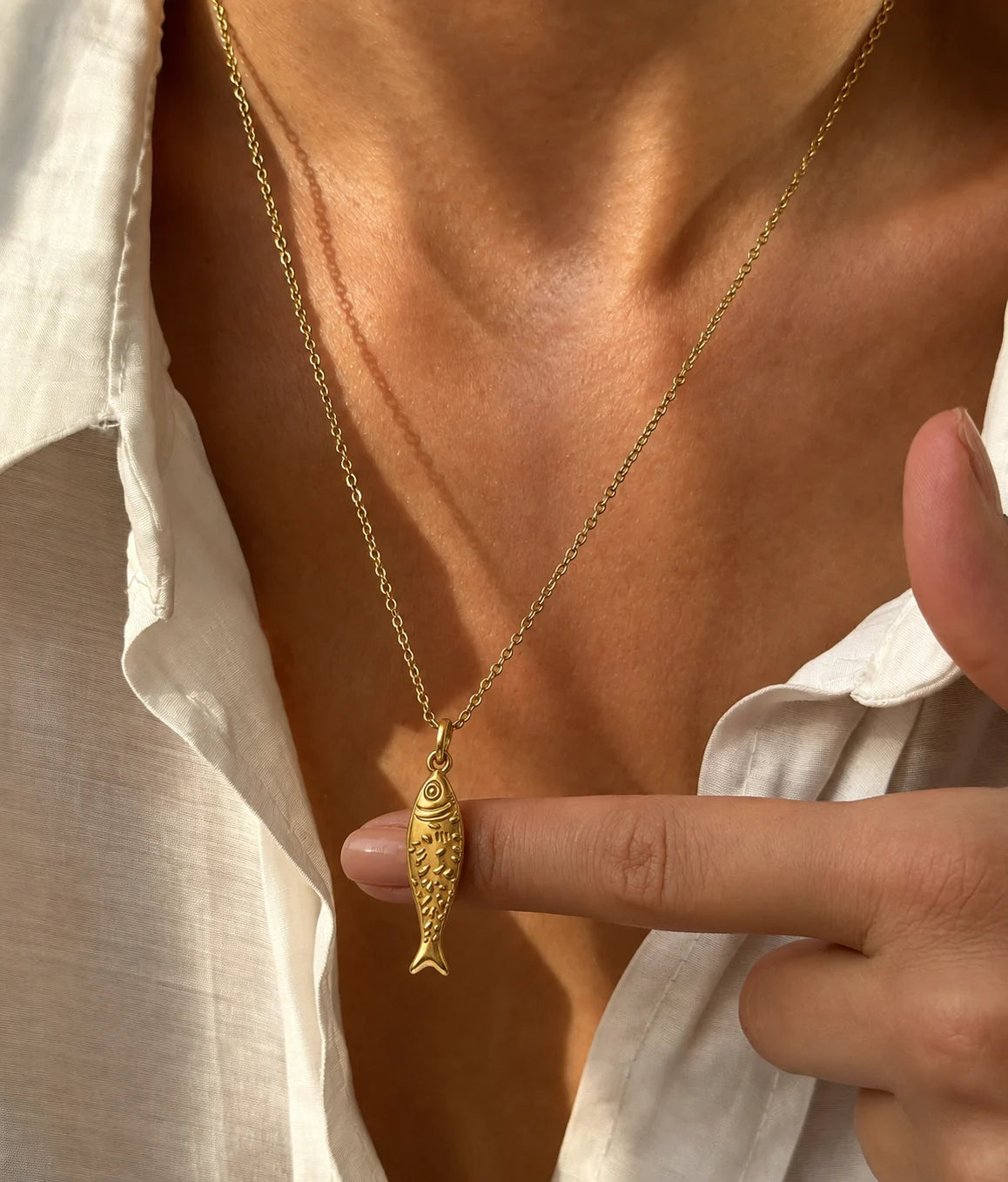 Lucky Fish Charm worn on a chain, fingers touching the charm, 18K gold PVD