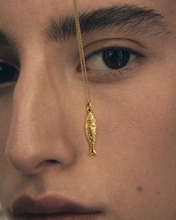 Lucky Fish Charm worn close to the face in a portrait – sweatproof, hypoallergenic charm