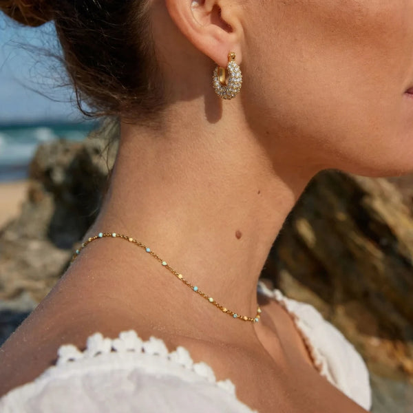 Lumi Pavé Huggies worn at the beach, 18K gold PVD