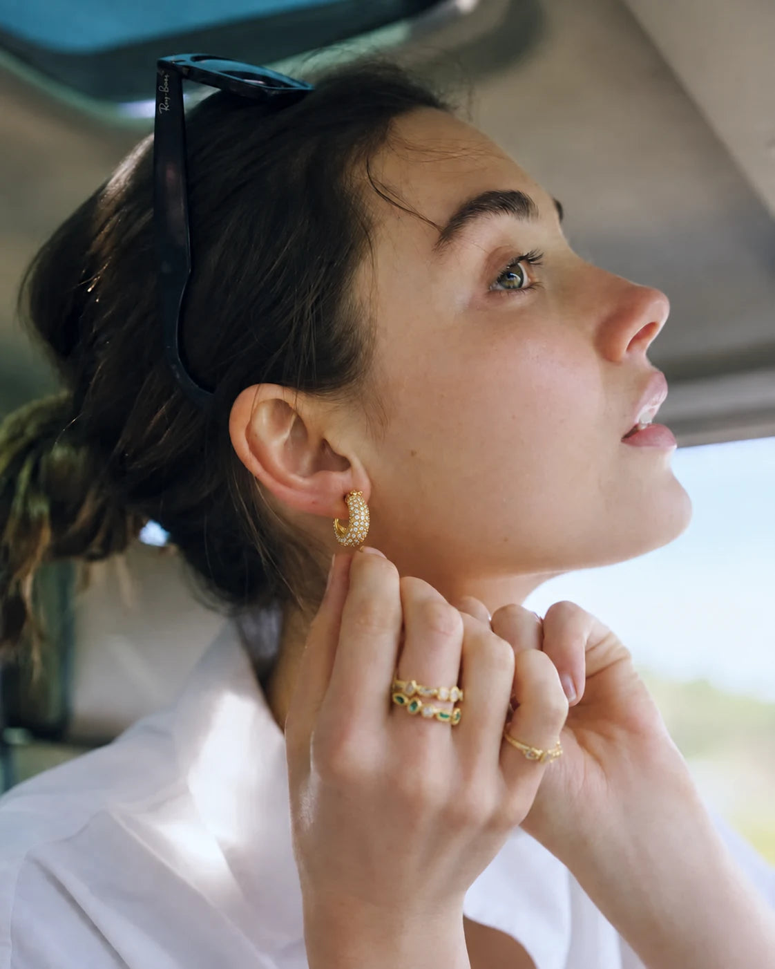 Lumi Pavé Huggies worn by a model in a car, waterproof gold huggie earrings