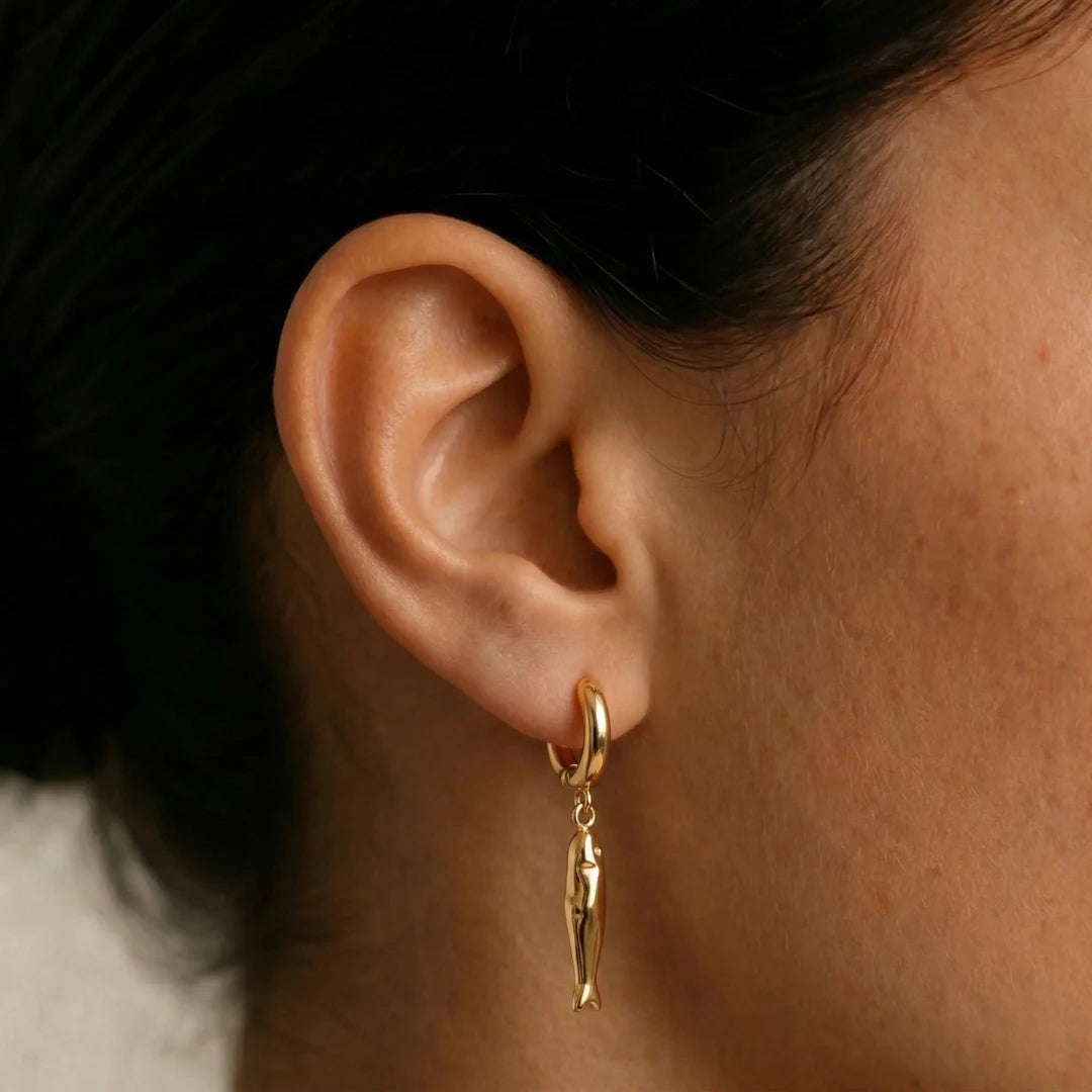 Matsya Hoops worn on the ear against a dark background, waterproof gold hoop earrings