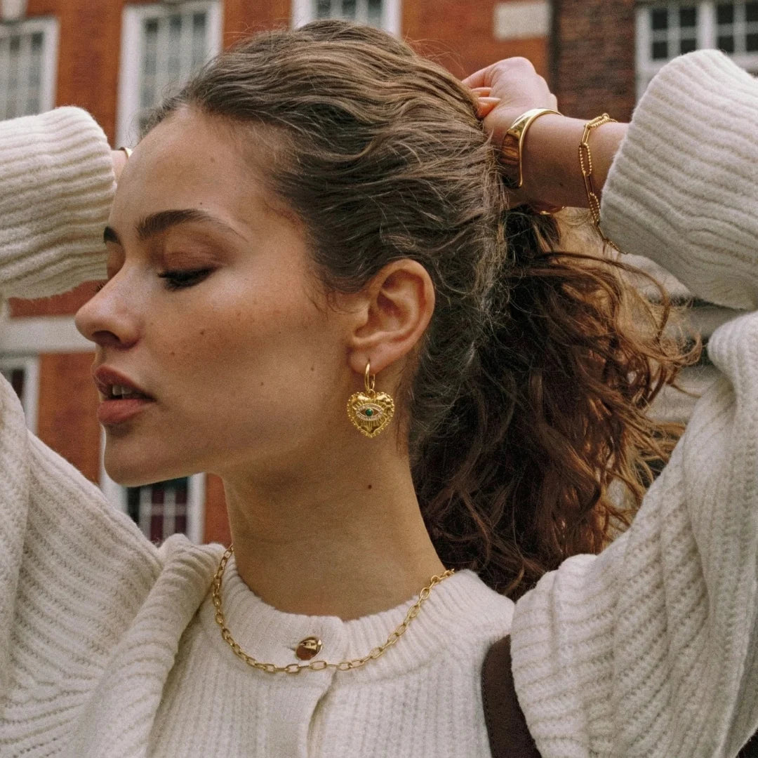 Nazar Heart Hoops worn by a model outdoors with hair up, 18K gold PVD