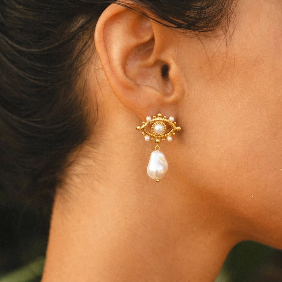 Pearl Nazar Drop Earrings worn on the ear with a black top, 18K gold PVD