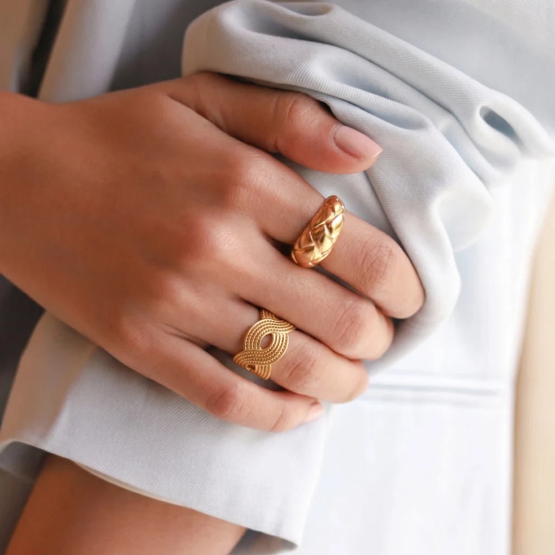 Tidal Wave Ring worn on the hand holding white fabric, 18K gold PVD